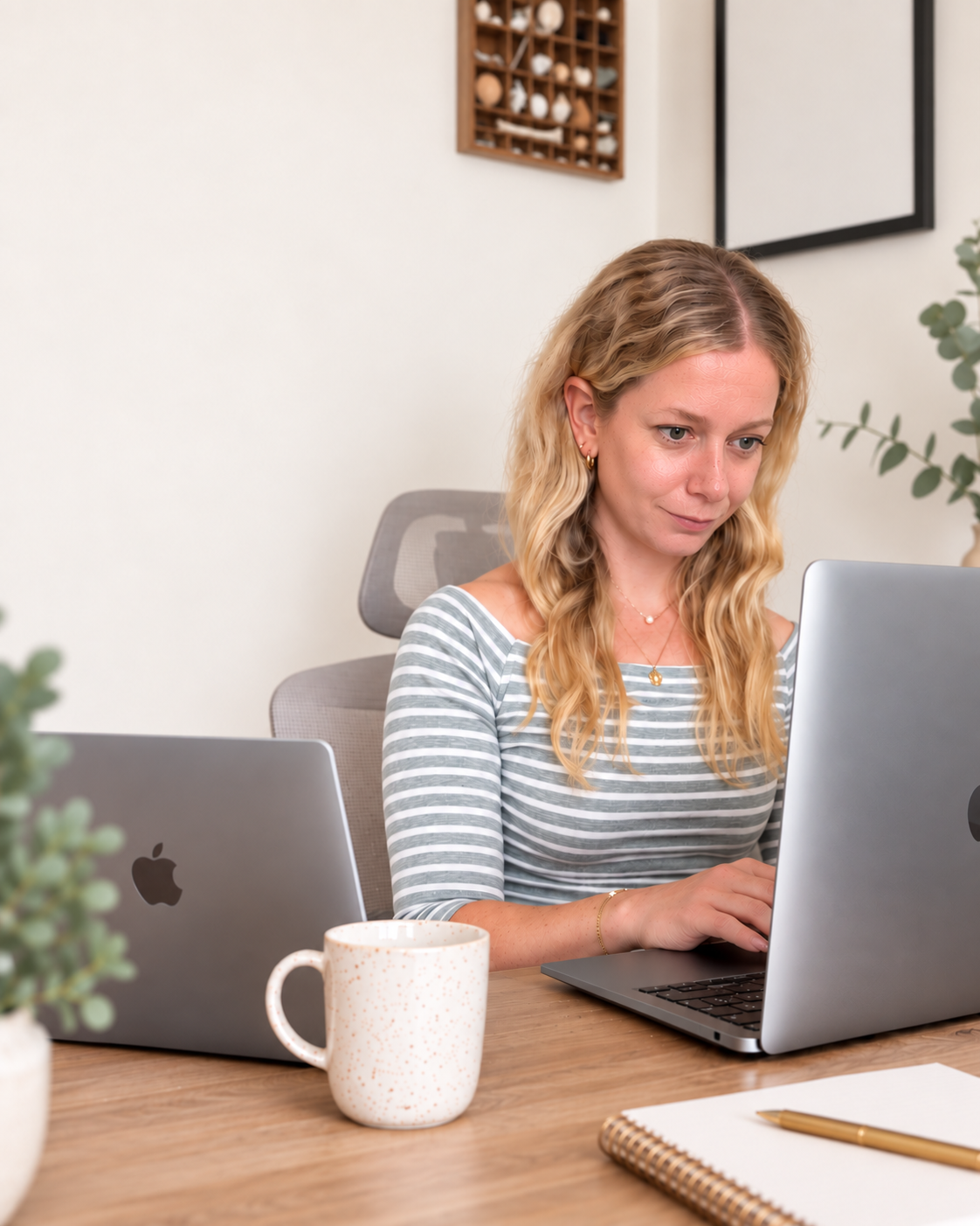 Ali working at her desk with two laptops